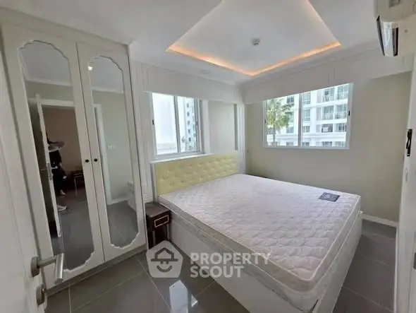 Modern bedroom with large windows and mirrored wardrobe in high-rise apartment.