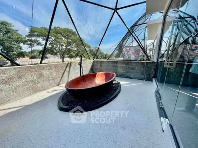 Unique outdoor bathtub on a spacious balcony with modern glass architecture and scenic views.