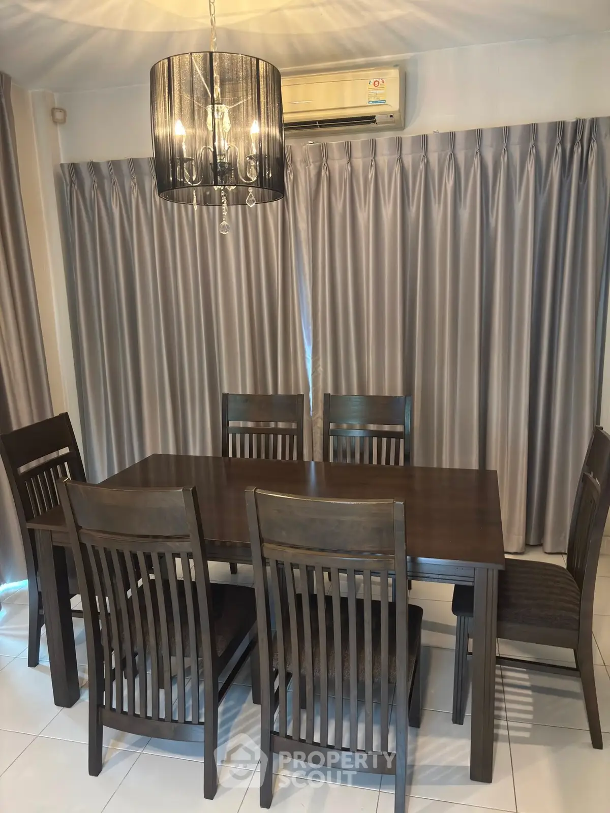Elegant dining room with dark wood table and chairs, modern chandelier, and air conditioning.