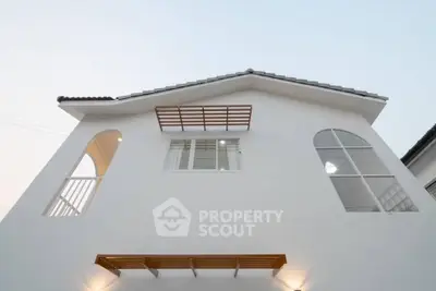 Modern white house exterior with unique architectural design and large windows.