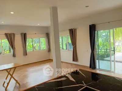 Spacious living room with large windows and garden view, featuring elegant flooring and modern design.