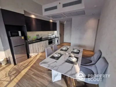 Sleek modern kitchen with high-end appliances and a stylish dining area, featuring a marble table and comfortable seating, perfect for entertaining.