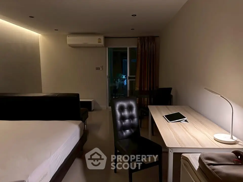 Modern bedroom with desk and tablet, featuring ambient lighting and sleek furnishings.