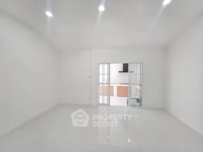 Spacious modern living room with sleek white tiles and sliding glass doors leading to a stylish kitchen.