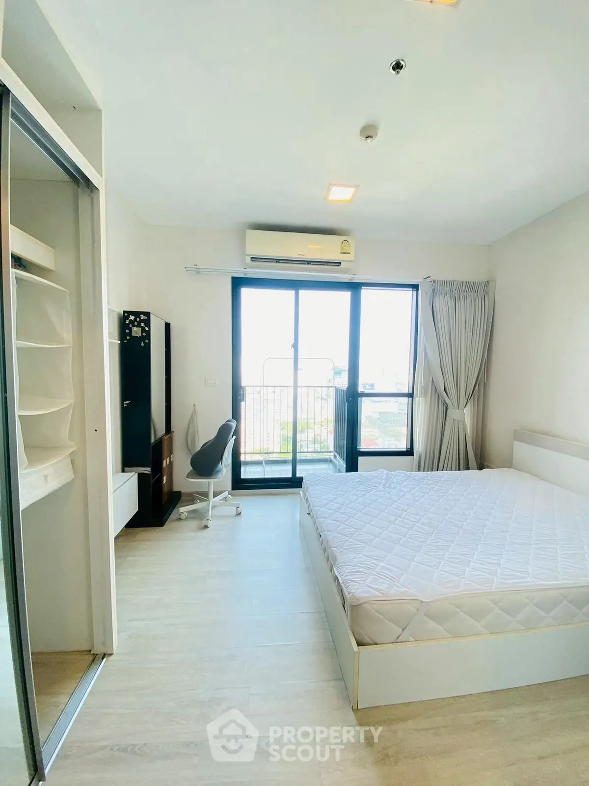 Bright modern bedroom with balcony view, featuring sleek furniture and ample natural light.