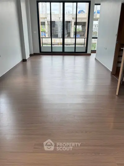 Spacious empty room with large windows and wooden flooring, ideal for customization.