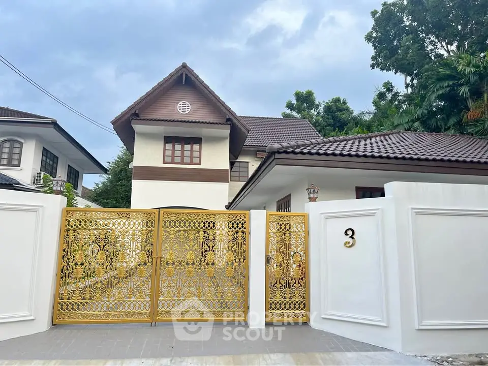 Luxurious house with ornate golden gate and elegant architecture in serene neighborhood.