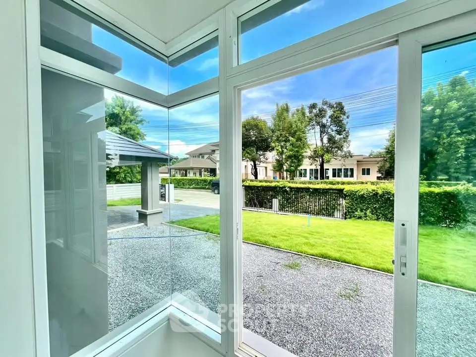 Modern home with large windows offering a stunning garden view, showcasing sleek architecture and lush greenery.