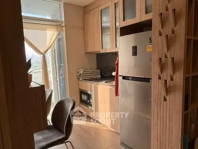 Modern kitchen with stainless steel fridge and wooden cabinetry, featuring natural light and cozy dining area.