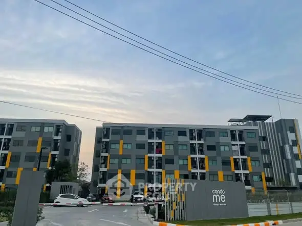 Modern condominium building with sleek design and ample parking space.