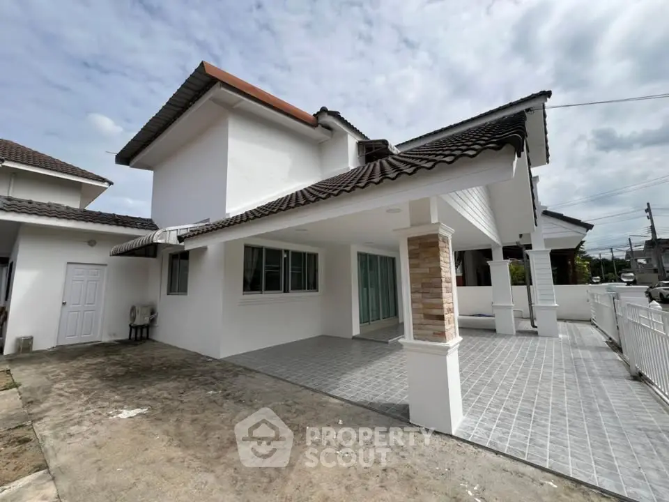 Spacious modern house with tiled patio and white exterior in a serene neighborhood.
