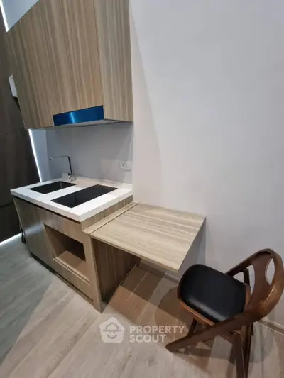 Modern compact kitchen with sleek wooden cabinetry and integrated appliances, perfect for urban living.