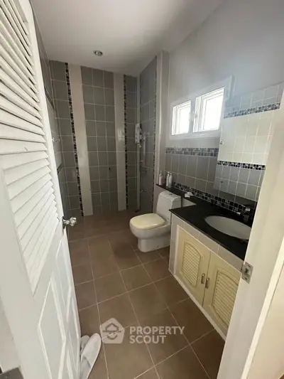 Modern bathroom with sleek design, featuring a shower, toilet, and stylish vanity in a bright setting.