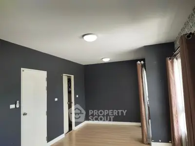 Spacious empty room with dark walls and wooden flooring, ready for customization.