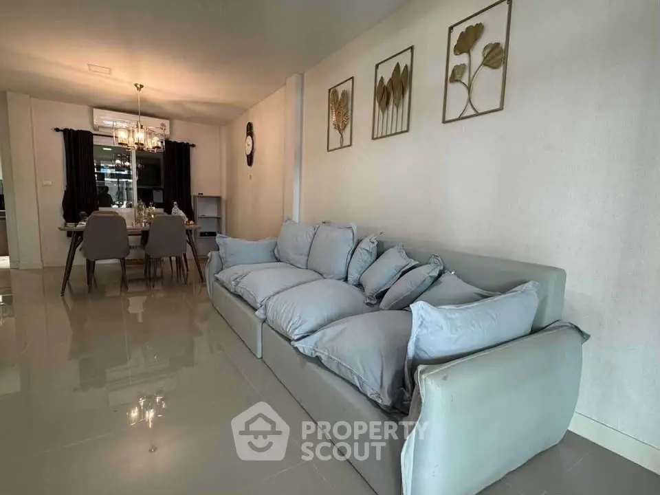 Spacious living room with elegant decor and dining area, featuring a plush sofa and stylish wall art.