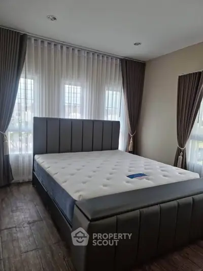Spacious bedroom with elegant bed and large windows, perfect for natural light lovers.