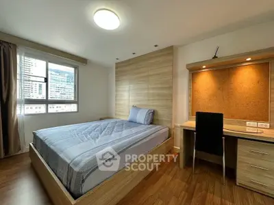 Modern bedroom with wooden flooring, built-in desk, and large window with city view.