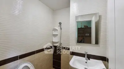 Modern bathroom with sleek design featuring a shower, sink, and toilet in neutral tones.