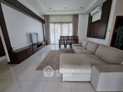 Spacious living room with modern sofa and dining area, perfect for family gatherings.