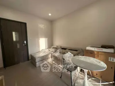 Modern living room with new furniture wrapped in plastic, featuring a cozy sofa and round table.