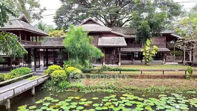 Charming traditional wooden house with lush garden and serene pond view.