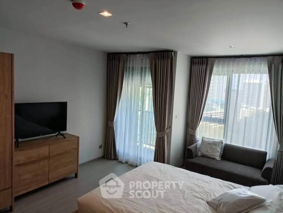 Spacious bedroom with modern decor and large windows offering city views