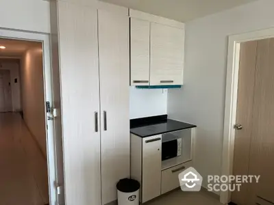 Modern kitchen nook with sleek cabinetry and built-in microwave in compact apartment.