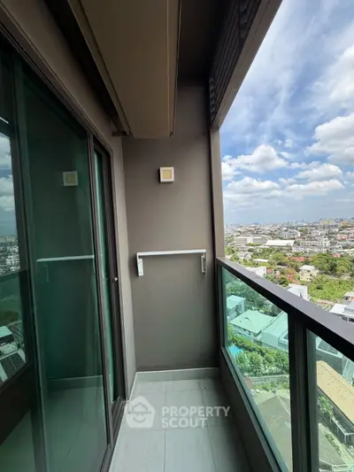 Modern balcony with glass railing offering panoramic city views under a clear blue sky.