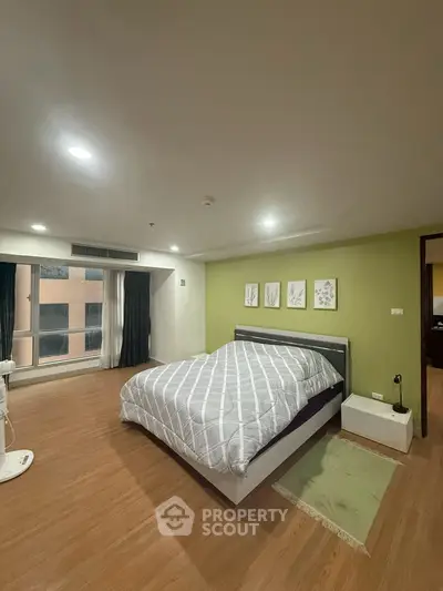Spacious bedroom with modern decor and large window offering natural light.