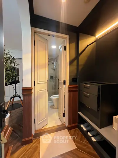 Modern interior hallway leading to a stylish bathroom with elegant wood flooring and sleek cabinetry.