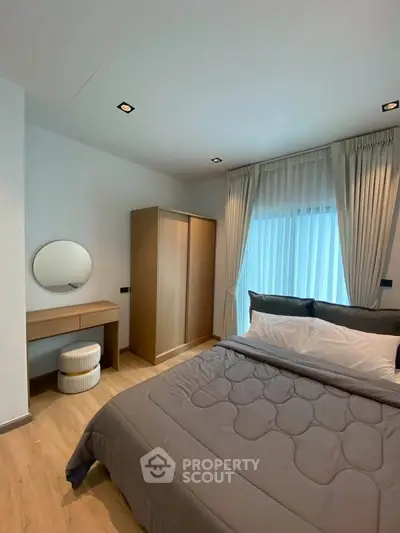Modern bedroom with stylish decor and natural light, featuring a cozy bed and elegant furnishings.