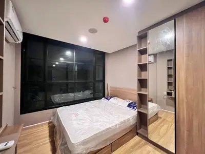 Modern bedroom with large window and wooden flooring in a stylish apartment.