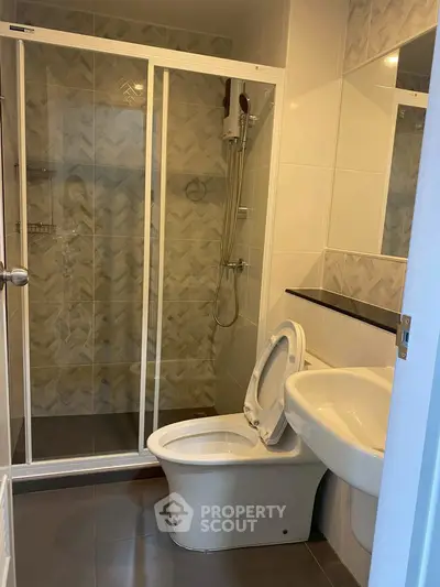 Modern bathroom with glass shower and sleek fixtures in contemporary apartment.