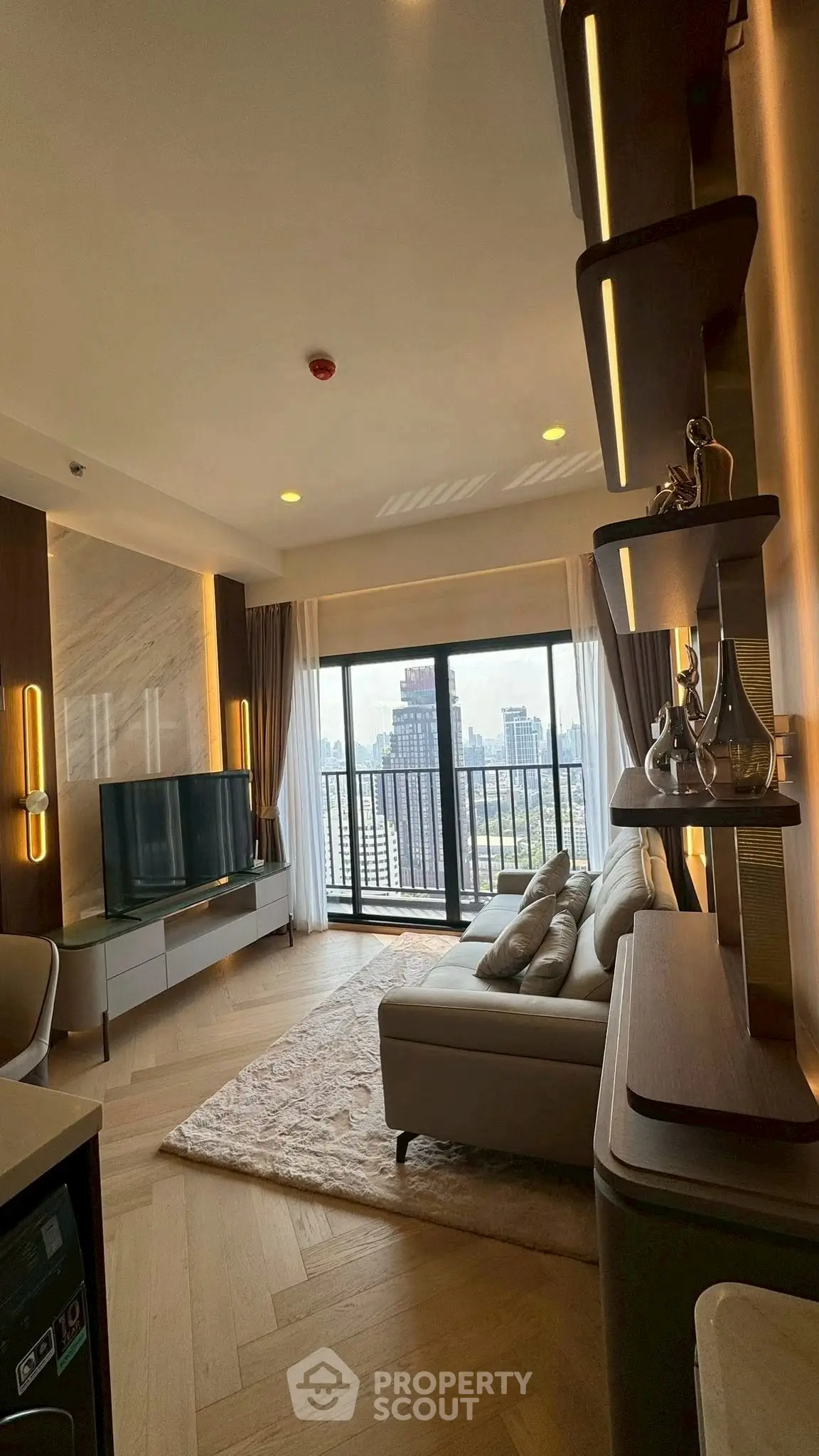 Luxurious living room with city view, elegant decor, and spacious balcony access.