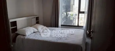 Cozy bedroom with city view, featuring a comfortable bed and large window for natural light.