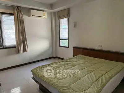 Spacious bedroom with natural light and modern air conditioning unit.