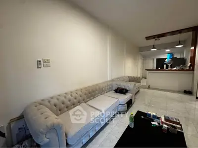 Spacious living room with elegant sofa and open kitchen layout, perfect for modern living.