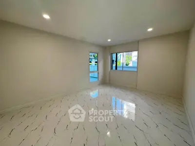 Spacious empty room with elegant marble flooring and large windows offering natural light.