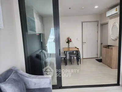 Modern apartment interior with glass partition, cozy dining area, and elegant decor.