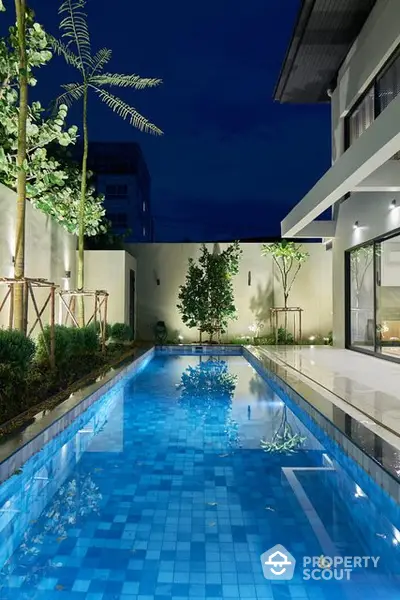 Luxurious modern home with a stunning illuminated pool at night, perfect for relaxation and entertainment.