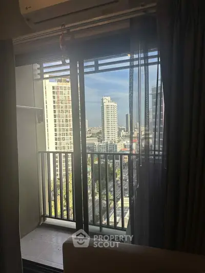 Modern apartment balcony with city skyline view through glass doors.