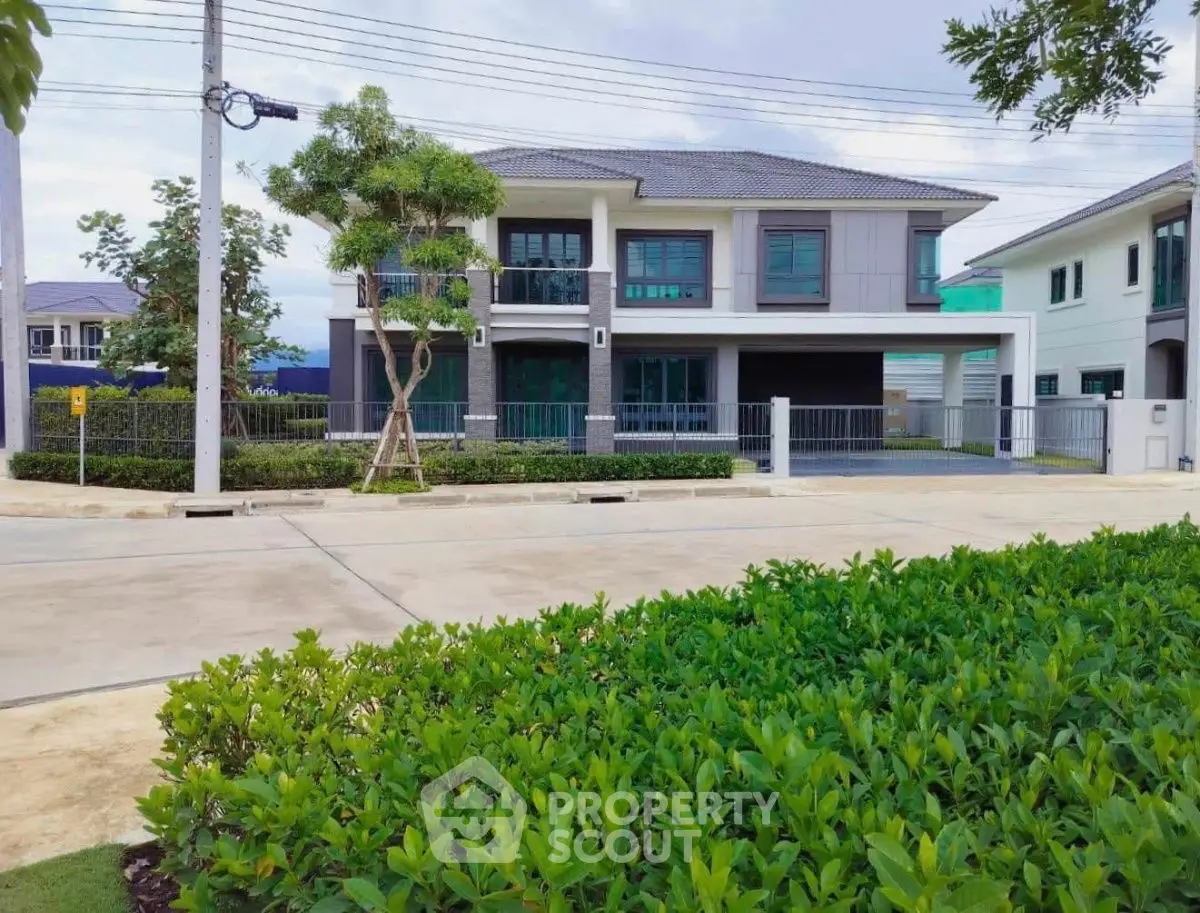 Modern two-story house with lush green garden and spacious driveway in suburban neighborhood.
