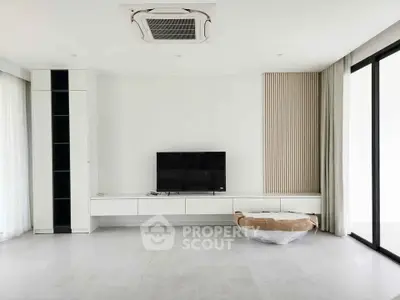 Modern minimalist living room with sleek TV unit and large windows.
