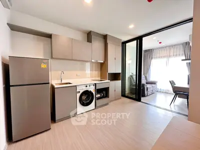 Modern kitchen with washing machine and open layout leading to a bright living room.