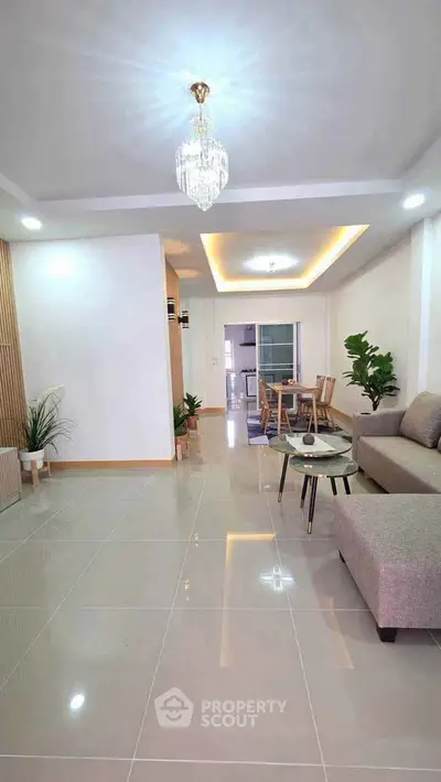 Spacious modern living room with elegant chandelier and open layout, perfect for stylish urban living.