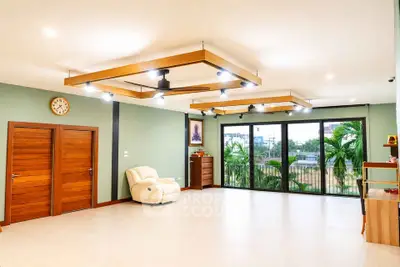 Spacious living room with modern lighting and large windows overlooking greenery.