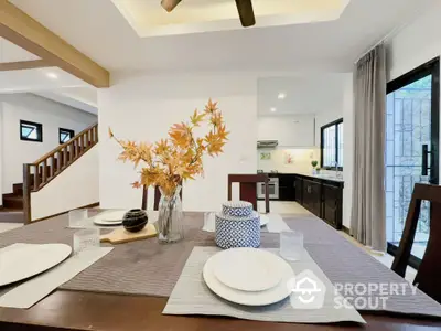 Modern dining area with elegant table setting and view into a sleek kitchen