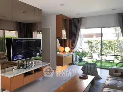 Modern living room with large windows and garden view, featuring stylish decor and ample natural light.