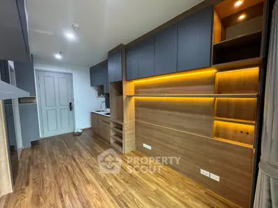 Modern apartment interior with wooden flooring and built-in shelving, featuring ambient lighting.