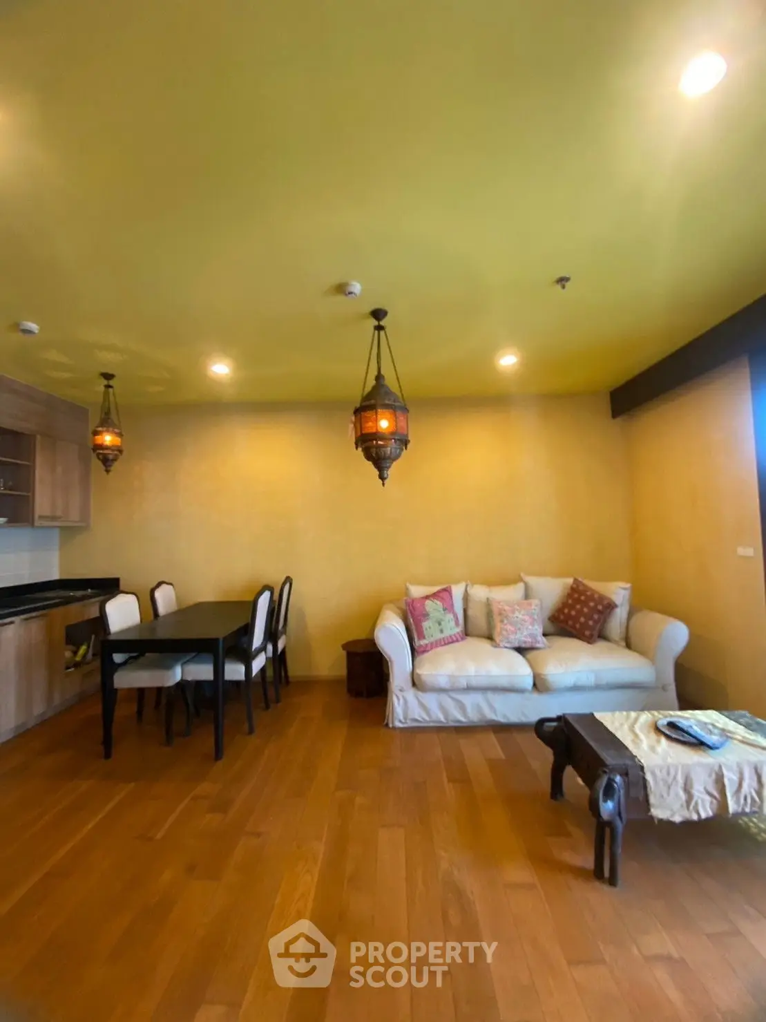 Charming living room with warm lighting and elegant decor, featuring a cozy sofa and dining area.